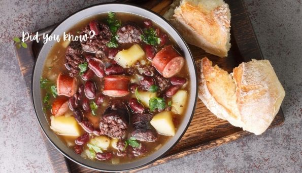 A hearty bean soup with sausage, potatoes, and herbs in a bowl, with crusty bread on a wooden board nearby (text 'Did you know?' visible).