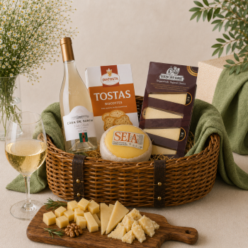 Gift basket featuring a bottle of white wine, cheeses, and crackers arranged with a cheese board in front, on a beige background.