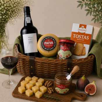 Gourmet gift basket with wine, cheese wheel, fig jam, crackers, and fresh figs/figs in a wicker tray lined with green cloths.