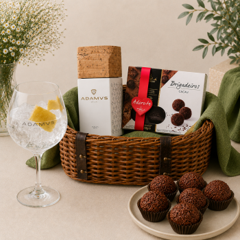 Gift basket with chocolates and a gin box, Brigadeiros, and chocolate truffles on a beige surface.