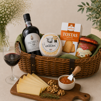 Gourmet gift basket with a bottle of port, wheel of cheese, crackers, jam, and sliced cheese arranged on a wooden board.