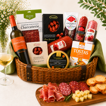Wicker gift basket filled with assorted meats, cheeses, crackers, and a bottle of wine on a table.